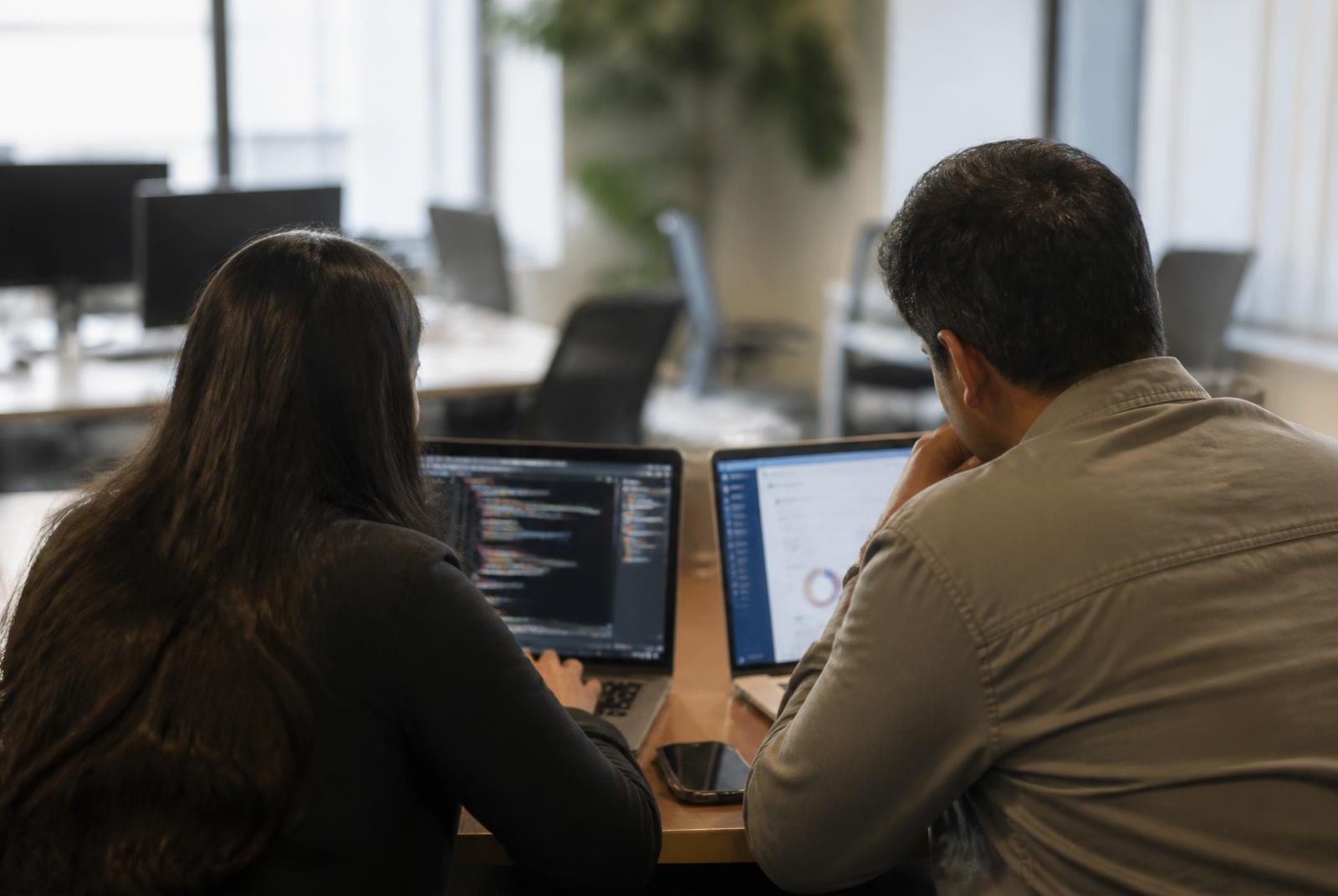 Twee Avensus specialisten werken samen achter een laptop op kantoor
